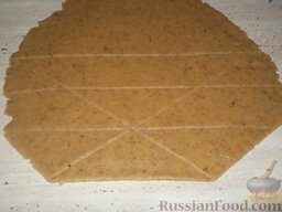 Рогалики песочные с орехами: Включить духовку.    Готовое тесто раскатать тонким пластом (0,4 см), нарезать на треуголь­ники с одним тупым концом и расстоянием между острыми углами 10 см