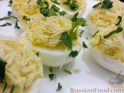 Яйца, фаршированные сыром и чесноком: Наполнить смесью желтков и сыра половинки белков. Яйца, фаршированные сыром с чесноком, посыпать сыром и зеленью петрушки.