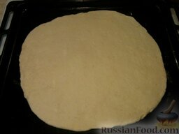 Пирог с сырой картошкой: Включить духовку для разогрева.    Колобки раскатать на лепешки. Сначала первый раскатать толщиной 1 см, переложить на противень.