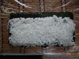 Суши по-домашнему: Теперь нужно перевернуть лист нори с прилипшим к нему рисом. Можно задачу упростить - накрыть вторым деревянным ковриком и перевернуть.