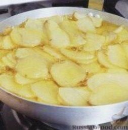 Испанский омлет с картофелем (тортилья): Картошку очистите и нарежьте кружками толщиной около 5 мм. Влейте масло в глубокую жаростойкую сковороду (желательно, с антипригарным покрытием). Добавьте картошку и готовьте ее в масле при небольшом кипении около 15 минут. Мягкую картошку (готовность проверьте острием ножа) выложите шумовкой в тарелку.