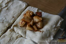 Слоёные пирожки с яблоками: Размороженное тесто разрезаем на квадратики. На них выкладываем яблочную начинку.