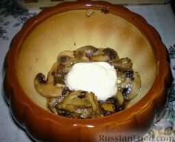Картошка в горшочках с грибами: В горшочки выкладываем половину обжаренных грибов и половину оставшихся белых грибов. Добавляем ложку сметаны.