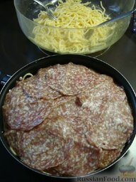 Омлет с макаронами: Смажьте сковороду маслом, выложите половину спагетти с яичной смесью, сверху выложите ломтики копченой колбасы.