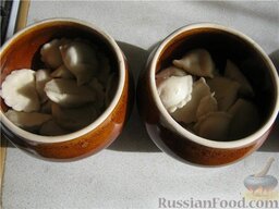 Пельмени, запеченные в горшочках: Пельмени переложить в керамические горшочки, добавить масло и сметану.