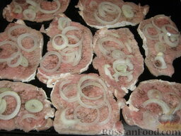 Свинина с ананасами и сыром: На мясо выкладываем кольца лука.