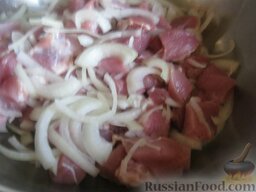Свинина, запеченная с картофелем: В миску сложить мясо и лук. Хорошо перемешать.