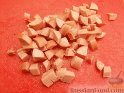 Слоеный салат "Зазеркалье": Если используются сосиски, а не колбаса, то их нужно отварить и снять шкурку. Затем нарезать кубиками.