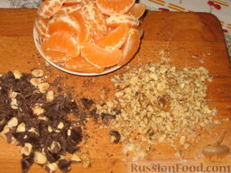 Рождественская мандариновая шарлотка: Мандарины очистим и разберем на дольки. Шоколад мелко порежем вместе с орехами. Грецкие орехи измельчим скалкой. Добавим все в тесто и вымешаем.