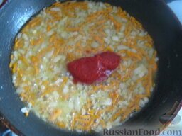 Суп из чечевицы с томатом: Разогреть сковороду, налить растительное масло. Обжарить, помешивая, лук и морковь 3-4 минуты на среднем огне. Затем добавить муку. Перемешать. Затем добавить томат. Потушить, помешивая, 1 минуту.