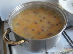 Суп гороховый с копченостями: Переложить тушеные овощи, мясо и копченые сосиски в суп. Варить под крышкой на маленьком огне 10-15 минут.