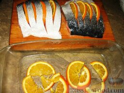 Апельсиновая семга: Затем со стороны шкурки надрезать рыбу поперек на порционные куски, но не до конца.  Апельсин порезать половинками кружочков и вставить их в надрезы. Оставшимся апельсином выстелить дно противня для запекания.