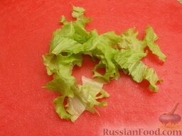 Салат с крабовыми палочками и редисом: Листья салата вымыть. Оставить 1-2 листа для украшения салата, остальные порвать руками или порезать.
