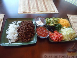 Мексиканские тако (taco): Кладем на большие тарелки приготовленное мясо, нарезанные овощи и зелень, добавляем сметану и сальсу.