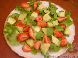Фруктовый салат из клубники и авокадо: Выкладываем на тарелку листья салата (целые или нарезанные). Сверху аккуратно выкладываем ломтики авокадо и клубники.