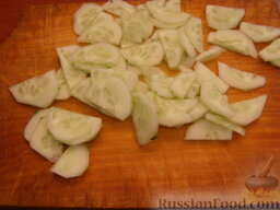 Овощной салат с тунцом: Огурцы вымыть, очистить от кожуры. Разрезать пополам, а затем тонкими ломтиками.