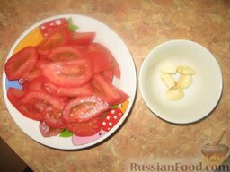 Жареные кабачки с помидорами: Нарезаем помидоры дольками, чистим чеснок.