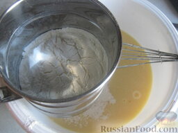 Пышные оладьи на кислом молоке: Добавить соду в миску. Понемногу добавлять просеянную муку, взбить венчиком тесто.