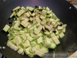 Овощная икра жареная: Добавить баклажаны к кабачкам, жарить под крышкой дальше (еще 10 минут), время от времени перемешивая.