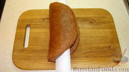 Шоколадный торт "Слоновья слеза": Готовый пирог выложить на доску, снять пергамент, положить на середину коржа качалку (скалку) и сложить горячий корж пополам.