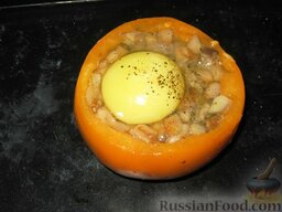 Яичница с ветчиной и грибами в помидоре: Разбить яйцо и осторожно вылить его в помидор сверху. Посолить и поперчить.   Поставить яичницу с ветчиной и грибами в помидоре запекаться в разогретую до 180-200 градусов духовку на 15-20 минут, пока яйцо не схватится.