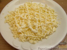Нежный крабовый салат: Выложить тертый плавленный сыр на тарелку, полить майонезом (сделать сеточку, используя примерно 1 ст. ложку соуса).