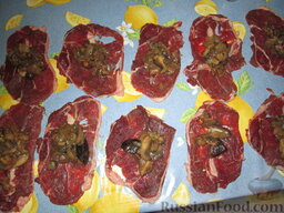 "Торбочки" из говядины с грибами: Начинку из грибов равномерно распределить, выложить на каждый ломтик мяса.