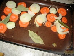 Щука, фаршированная кусочками: Порезать кружочками вторую луковицу и морковь, выложить на противень, разложить лавровые листы и перцы горошком.