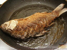 Караси, жаренные "без костей": Через 3-5 минут, когда нижняя половинка рыбы основательно подрумянится, аккуратно перевернуть рыбу на другую сторону и жарить еще 3-5 минут.  Затем карася жареного вынуть. Если нужно еще жарить рыбу, то долить масло, снова нагреть его. Можно снова на 20-30 секунд опустить в масло чеснок (новые зубки).