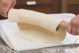 Классическая сырная пицца: 6. Металлический лист без бортиков застелить пергаментом. Круг теста аккуратно намотать на скалку и переложить на пергамент.