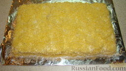 Закусочный торт из лаваша: Натереть сыр на мелкой терке, распределить его равномерно сверху и по бокам.