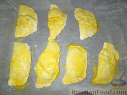 Сочни с ветчиной, сыром и грибами: Залепить края, смазать взбитым желтком, выложить на противни, покрытые бумагой для выпечки.