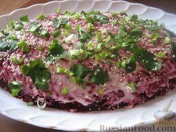 Салат "Копченый кальмар в шубе": Украсить салат с копченым кальмаром под шубой зернами кунжута, зеленью и зеленым луком. Оставить на 2-3 часа в холодильнике для пропитки.