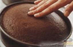 Шоколадный торт с масляным кремом: 5. Выложить тесто в подготовленные формы и поместить в разогретую духовку, выпекать коржи для шоколадного торта около 30-35 минут, до чистой деревянной палочки. Готовым коржам дать постоять в формах минут 10, а затем перевернуть на решетку, удалить формы и снять пергамент. Оставить коржи на решетке до полного охлаждения.     6. Приготовить шоколадный крем. В миску  выложить сливочное масло и взбить до пышного состояния. Насыпать в масло половину сахарной пудры, хорошо перемешать, постепенно ввести оставшуюся сахарную пудру и ванильный экстракт. Шоколад разломать на кусочки и растопить на водяной бане или в микроволновке.     7. Растопленный шоколад ввести  в масляный крем, хорошо перемешать.
