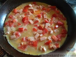 Омлет с ветчиной и помидорами: Разогреть сковороду, добавить масло. Влить 2/3 части яичной массы. Уменьшить огонь до маленького. Через минуту равномерно выложить начинку.