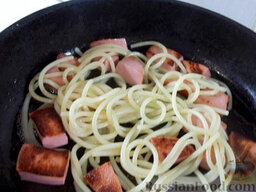Спагетти с колбасой, яйцом и зеленью: Когда колбаса подрумянится, добавьте спагетти и все перемешайте.