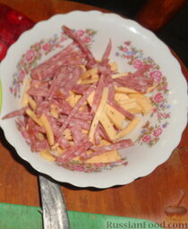 Закусочный салат с колбасой и сыром: Смешиваем колбасу и сыр.