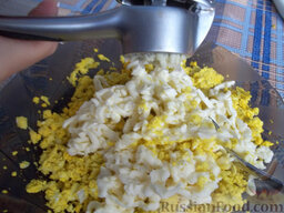 Яйца, фаршированные икрой минтая и плавленым сыром: Чеснок очистите и выдавите через пресс в начинку. Добавьте майонез и перемешайте.