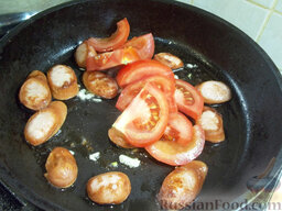 Яичница с сосисками и помидорами: Помидоры помойте, нарежьте полукольцами и сразу же выложите в сковороду.