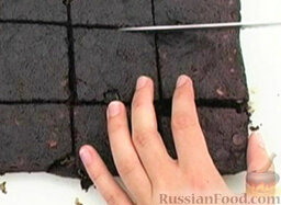 Шоколадно-ореховый пирог: Разрезать шоколадно-ореховый пирог на квадратики и посыпать сахарной пудрой.
