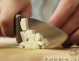 Сибас, запеченный в "панцире" из соли: Очистить и мелко нарезать чеснок.