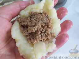 Картофельные зразы с мясом: Возьмите в руку небольшую часть пюре.  Сверху выложите фарш, прикройте еще картофельным пюре и сформируйте картофельные зразы с мясом в виде котлеток.