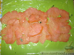 Рулетики из красной рыбы и свежего сыра: Ломтики копченой красной рыбки выложить в один слой на пищевую пленку.