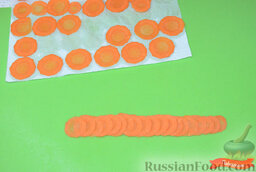 Украшение из овощей: роза из моркови: На бумажное полотенце или салфетку выложить кружочки, накрыть вторым полотенцем, промокнуть. Убрать верхнее полотенце. Выложить морковь тонкой полоской, чтобы краешек кружочка заходил на другой кружочек.