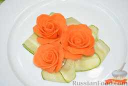 Украшение из овощей: роза из моркови: Выложить розу на блюдо. Огурец нарезать тонкими слайсами. Прикрыть зубочистки полосками огурца (или зеленью петрушки).