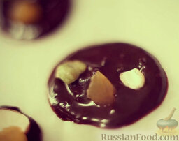 Десерт из шоколада с орехами и курагой: Пока шоколад не застыл, украсить десерт из шоколада курагой и орехами.