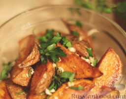 Картофель по-деревенски: Вынуть шумовкой картофель из масла. Добавить нарезанную петрушку, чеснок, соль. Перемешать.