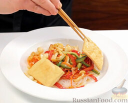 Рагу с грибами в азиатском стиле, с тофу и рисовой лапшой: Выкладываем на сервировочную тарелку рисовую лапшу. Сверху - тушеные овощи. Не забываем про тофу. Рагу с грибами и лапшой украшаем кунжутом.