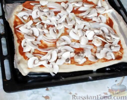 Пицца с грибами и морепродуктами: Выложить грибы на пиццу, распределяя их равномерно.