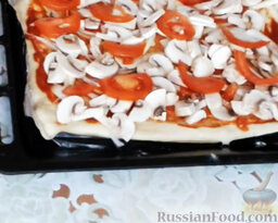 Пицца с грибами и морепродуктами: Помидор нарезать тонкими дольками и выложить поверх грибов.